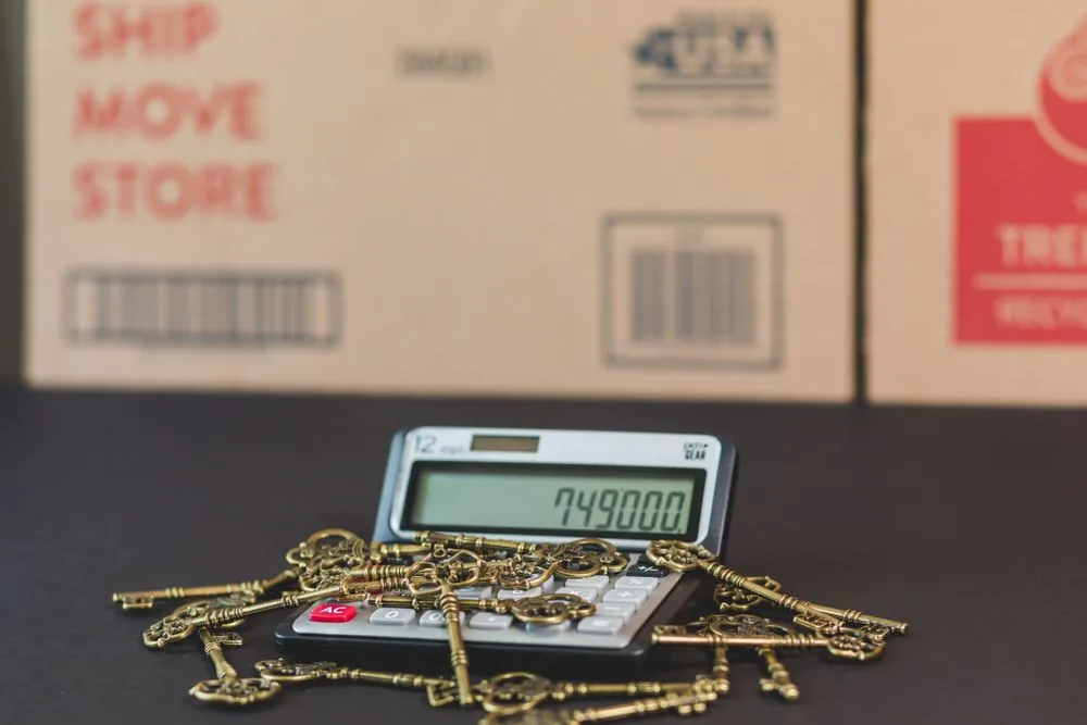 Gold house keys resting on a mortgage calculator